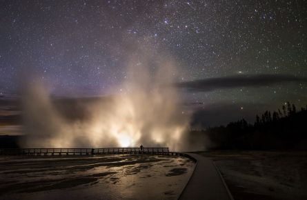 Car headlights illuminate the steam plume from Excelsior Geyser in the Midway Geyser Basin