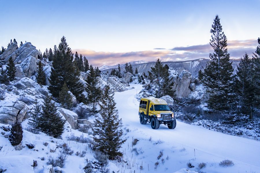 Snowcoach driving through the hoodoos at sunrise