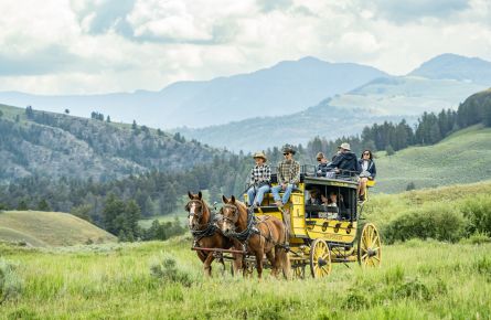 Stagecoache in a valley with mountains in the background